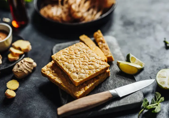 Pezzi di tempeh in agrodolce pronti per essere cucinati, con zenzero, lime e menta.