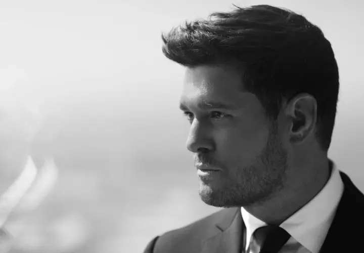 Michael Bublé w garniturze, zamyślony. Jego ponadczasowe michael bublé utwory brzmią jak jego spojrzenie.