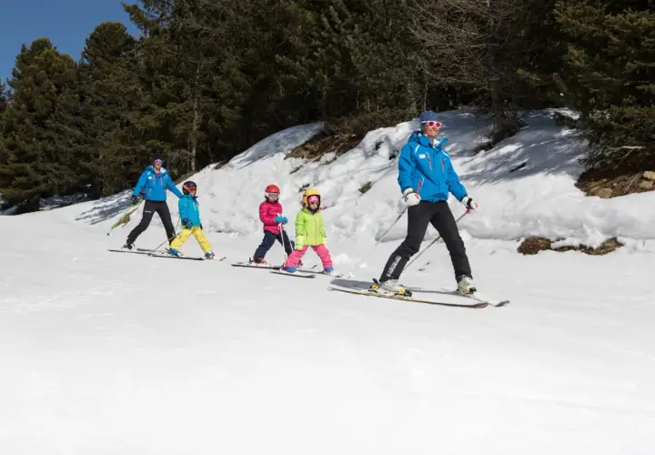 Maestro di sci guida bambini su piste innevate, un'ottima idea per dove sciare con bambini.