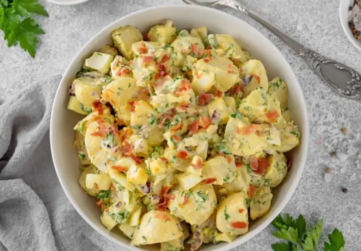 Deliciosa ensalada de patata cremosa con trozos de huevo duro, tocino crujiente y perejil fresco.