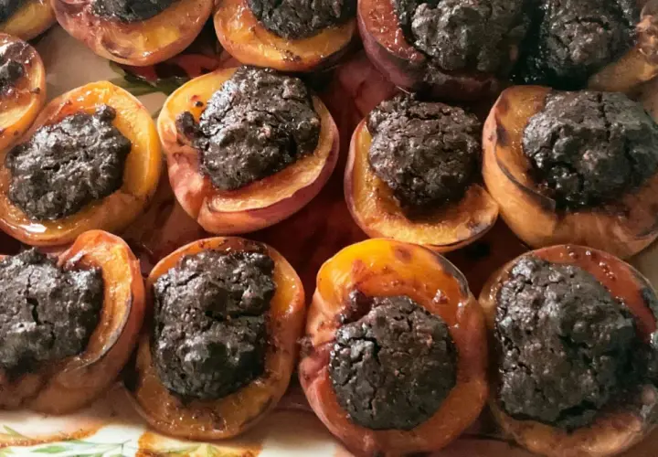 Deliziose pesche ripiene al forno, con un ripieno scuro e invitante, pronte per essere gustate.