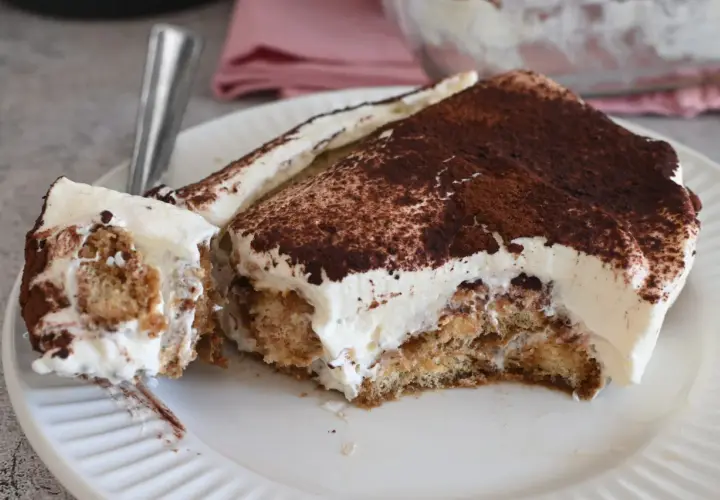 Fetta di tiramisù con abbondante crema al mascarpone 500 g, cosparsa di cacao amaro.