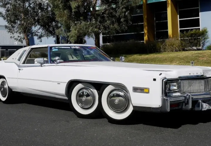 Biały Cadillac Eldorado z podwójnymi kołami z przodu i z tyłu. Ten niezwykły samochód ma aż cztery osie, co czyni go wyjątkowym na drodze.