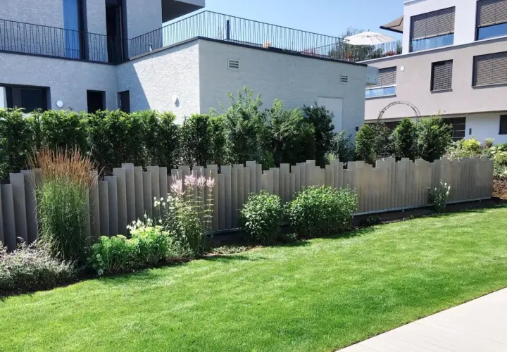 Moderne Zaunelemente bieten tolle **Sichtschutz Garten Ideen**. Ein gepflegter Rasen und üppige Pflanzen ergänzen die Architektur.
