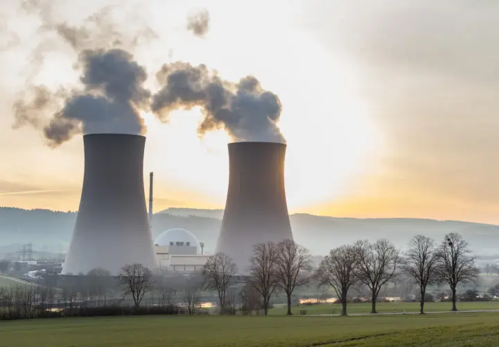 Dwie chłodnie kominowe elektrowni atomowej na tle zachodzącego słońca. Warto wiedzieć, ile prądu produkuje elektrownia atomowa.