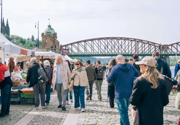 Tłum ludzi na targu, most w tle. Może to być scena z jednego z miast w rankingu miast w Polsce.