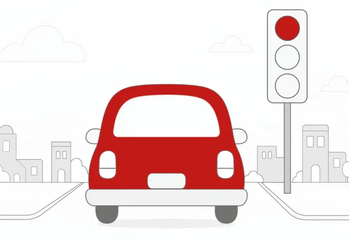 Czerwony samochód zatrzymał się przed sygnalizatorem świetlnym. Czerwone światło oznacza stop, aby uniknąć mandatu.
