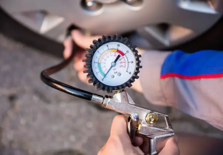 Manómetro de presión de neumáticos conectado a la válvula de una rueda. Aprende como saber la presion de las ruedas del coche para mayor seguridad.