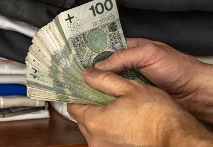 Dłonie trzymające plik banknotów 100 zł. Symbol oszczędności Polaków, być może na czarną godzinę lub na wymarzone wakacje.