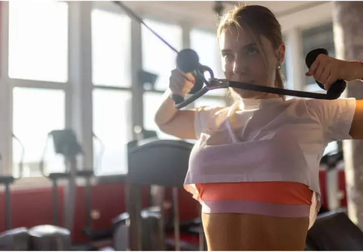 Junge Frau macht Face Pull am Kabelzug im Fitnessstudio.