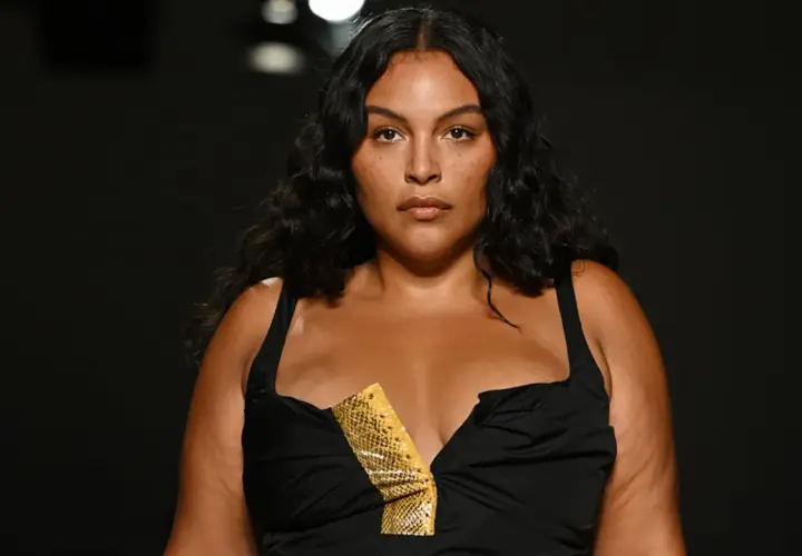 Modelo curvy con cabello oscuro y piel bronceada, luce un vestido negro con escote pronunciado y detalle de estampado de serpiente.