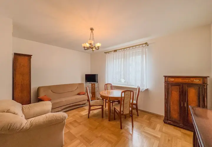 Przytulny salon z kanapą, fotelem i stołem z krzesłami. Klasyczne meble tworzą atmosferę domowego ciepła w tym aurec home.