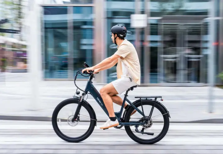 Hombre en bicicleta eléctrica, disfrutando de una marcha cicloturista urbana. El fondo borroso sugiere movimiento rápido y moderno.