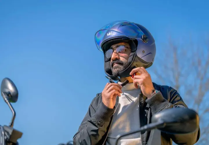 Uomo con casco blu metallizzato, pronto per un giro in moto. Il casco taglia 58 a cosa corrisponde? Probabilmente una misura media, perfetta per lui.