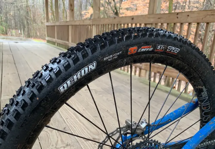 Maxxis Rekon tire on a wet wooden bridge. These tires are great for trail riding, offering excellent grip and durability.