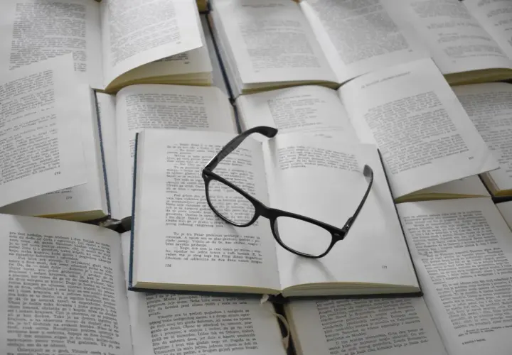 Lunettes posées sur des livres ouverts. Ces figures de style servent à enrichir le texte et à rendre la lecture plus captivante.