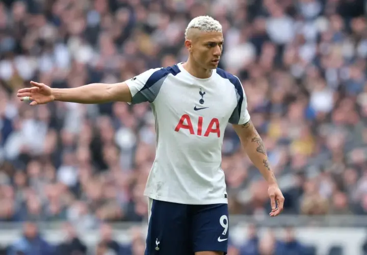 Piłkarz Tottenhamu z blond włosami w białej koszulce z logo AIA na tle trybun.