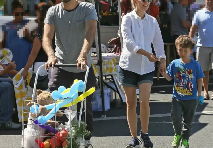 Natalie Portman z dziećmi na targu. Syn trzyma ją za rękę, a w wózku widać pluszowego misia i balony.