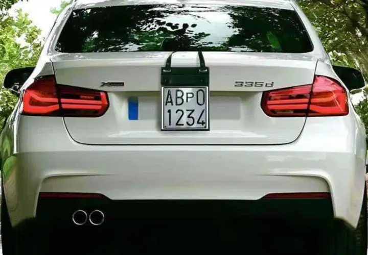Parte posteriore di un'auto bianca con targa prova "ABPO 1234" appesa.