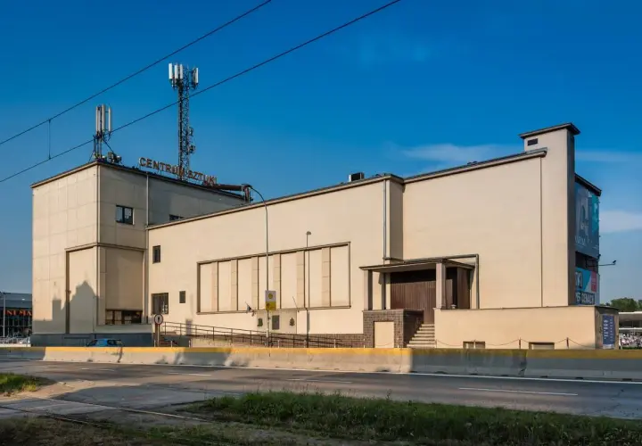 Betonowy budynek z napisem "CENTRUM SZTUKI" na dachu, z wieżami telekomunikacyjnymi. Obok widoczna droga i zieleń.