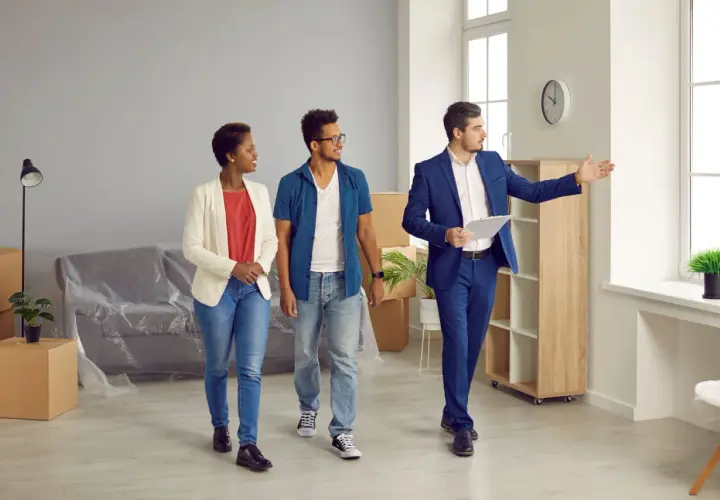 Un agent immobilier présente un appartement à un couple. Ils consultent leur checklist visite appartement.