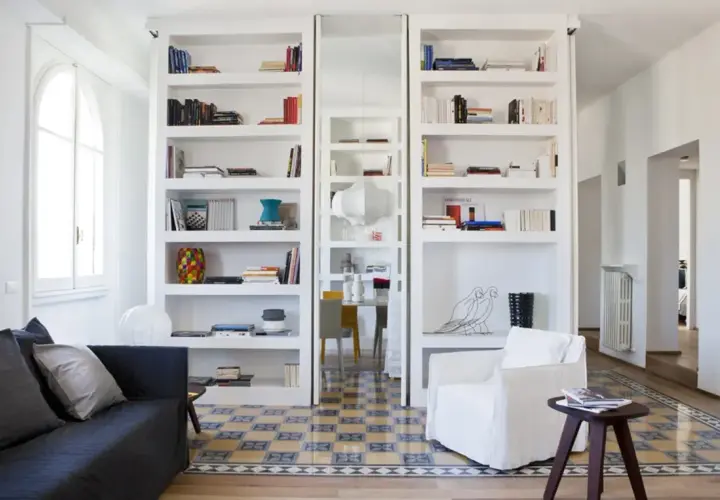 Parete divisoria in cartongesso con librerie bianche e nicchie decorative.