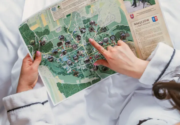 Ręka wskazuje na mapę Nałęczowa, planując, kiedy są wakacje i co zwiedzić.