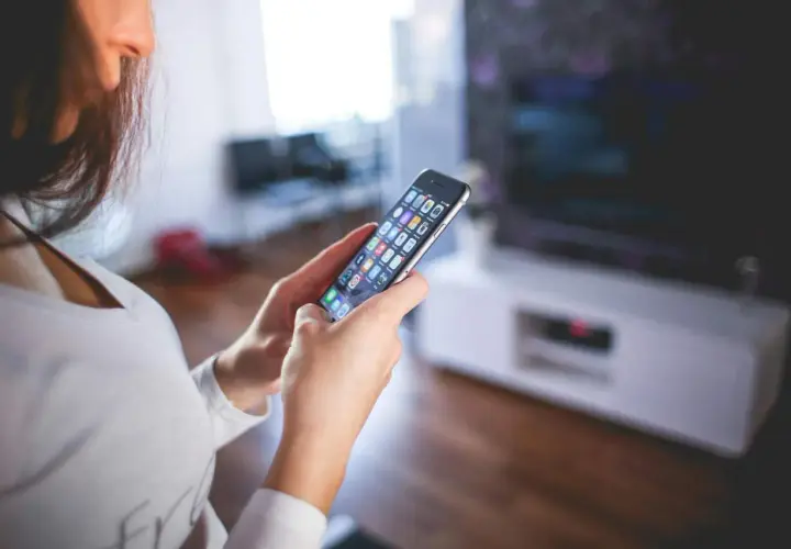 Kobieta steruje inteligentnym domem przez aplikację na smartfonie. Czy to smart life, czy Tuya?
