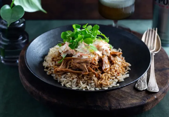 En tallrik med pulled pork med ris, toppad med en krispig coleslaw och färska örter. En härlig måltid!