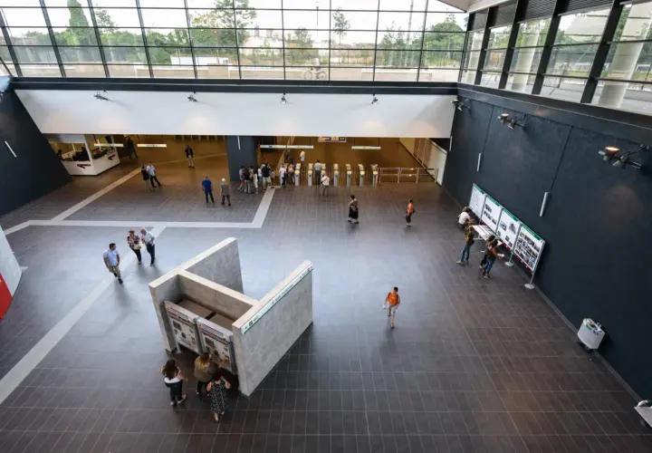 Interno moderno della fermata Teano metro C, con persone che acquistano biglietti e si dirigono verso i tornelli.