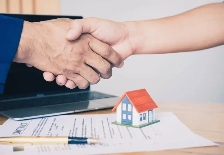 Poignée de main sur un contrat immobilier, symbolisant un accord respectant la loi du 6 juillet 1989 sur les réparations locatives.