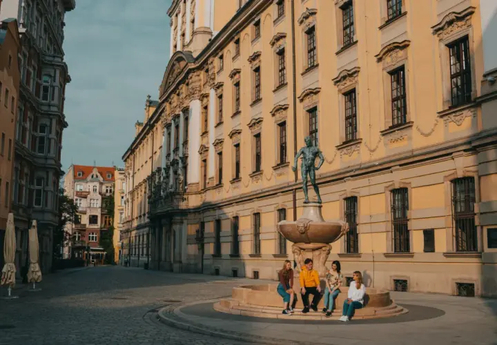 Studenci na wrocławskim Rynku, marzący o doktoracie. Słoneczny dzień, zabytkowa architektura.