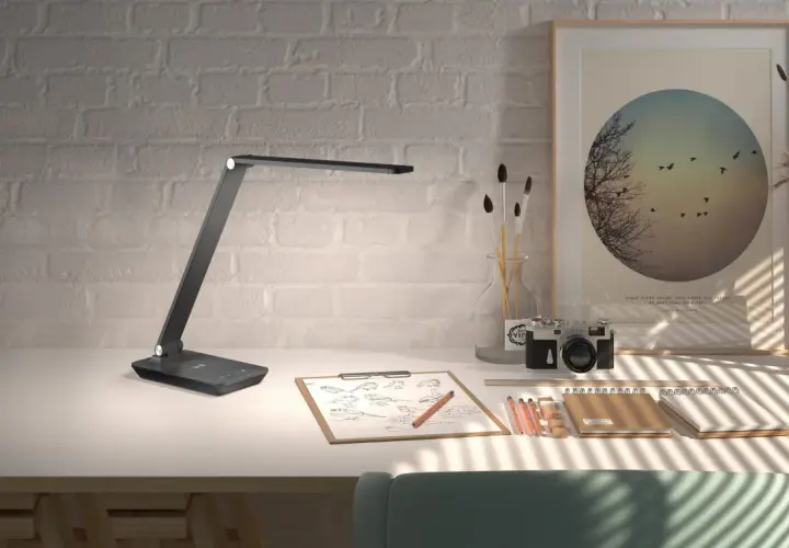 Flexo LED USB moderno sobre escritorio con cámara antigua, bocetos y arte.