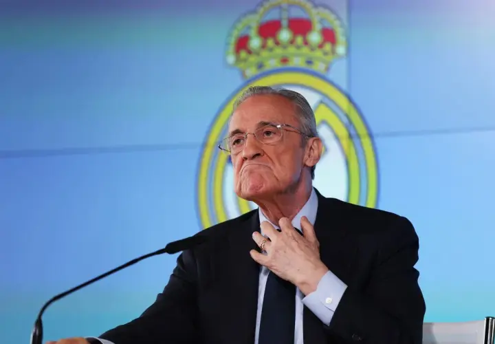 Florentino Pérez, prezes Realu Madryt, w garniturze i okularach, przemawia na tle klubowego logo.