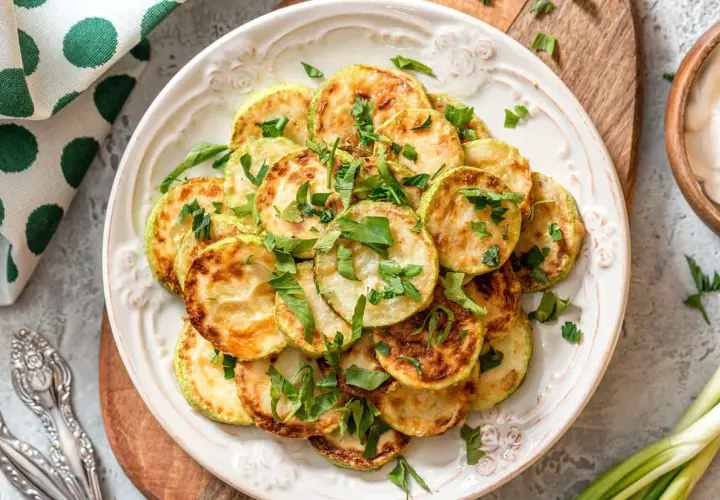 Fette di zucchine dorate e profumate, un'idea per una ricetta zucchine light veloci e gustosa, guarnite con prezzemolo fresco.