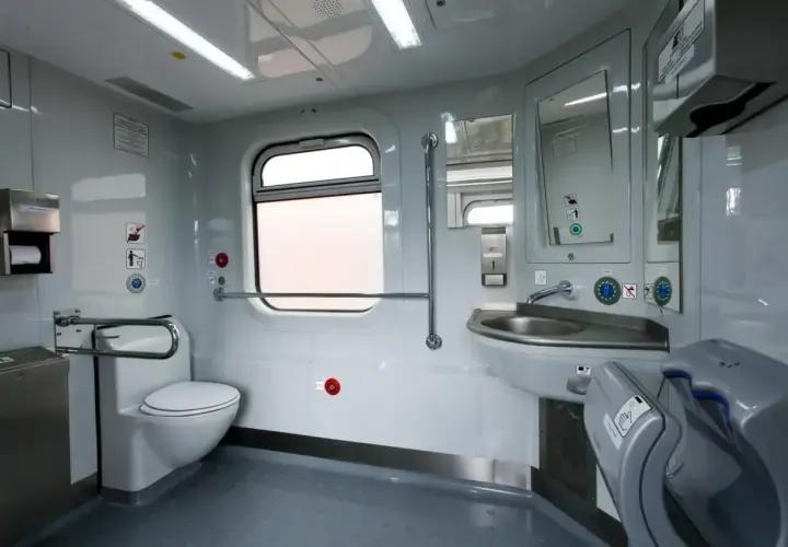 Wnętrze toalety w pociągu Pendolino: biała muszla klozetowa, umywalka, lustro, suszarka do rąk i okno.