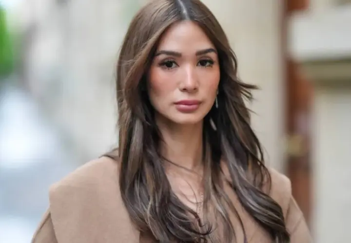 Mujer con cabello castaño largo y ondulado, viste un abrigo color camel. Su maquillaje old money resalta su belleza natural con tonos suaves y elegantes.