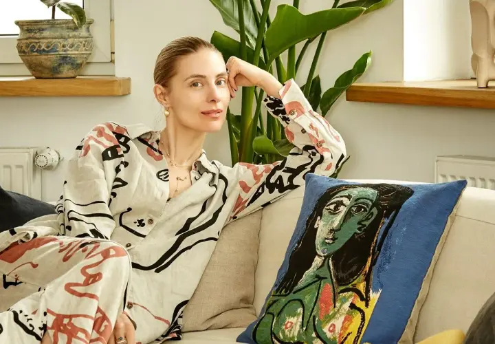 Katarzyna Zawadzka w domowym zaciszu, relaksująca się na kanapie obok poduszki z motywem Picassa. Jej życie prywatne pełne jest sztuki i spokoju.
