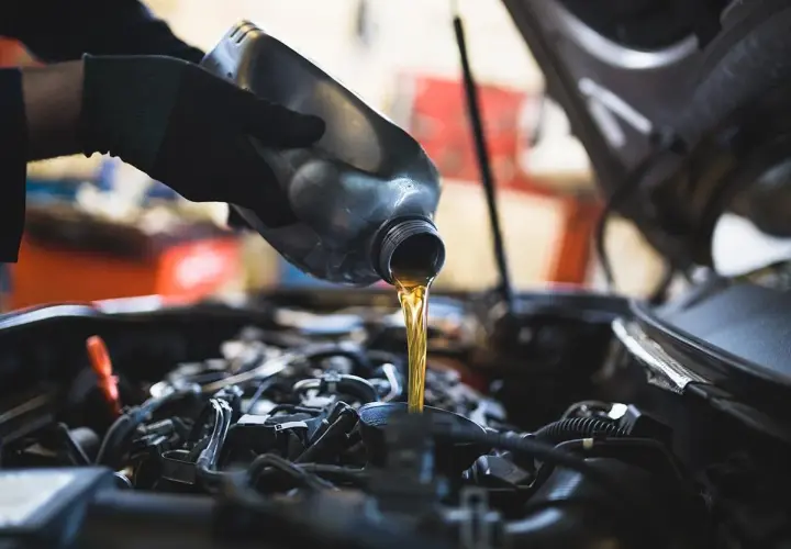 Mano con guanto versa olio motore. Un'operazione di cambio olio per un cambio manuale.