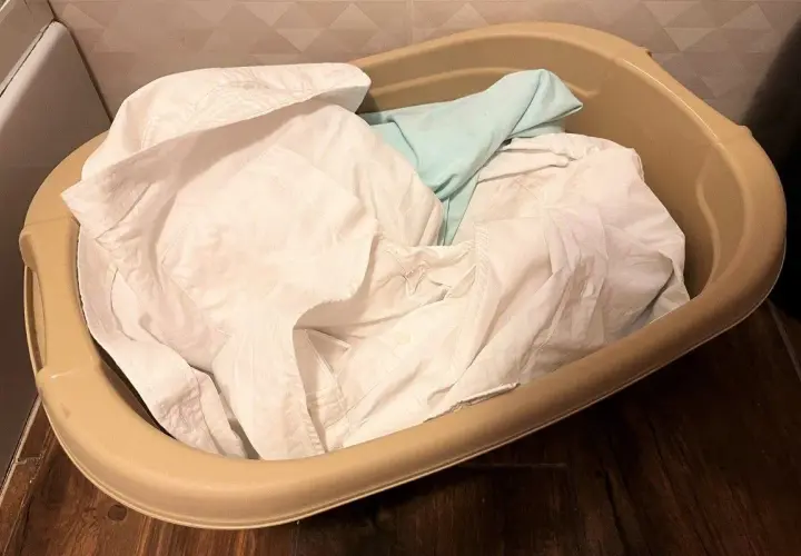 Brudne ubrania w koszu, gotowe do prania. Czas dowiedzieć się, jak pozbyć się zapachu potu z odzieży.
