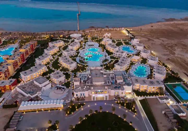 Widok z lotu ptaka na luksusowy resort Casa Blue, z basenami, budynkami i morzem w tle, oświetlony wieczorem.