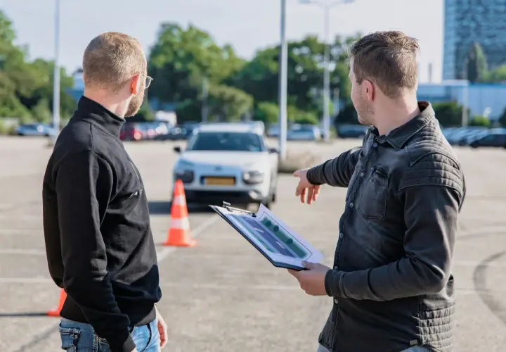 Egzaminator wskazuje na plan placu manewrowego, omawiając jak wygląda egzamin praktyczny kat B.