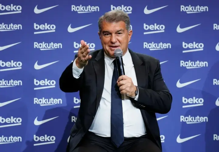 Joan Laporta, prezydent FC Barcelona, przemawia na tle logo klubu. Jego słowa kształtują przyszłość drużyny i jej trenerów.