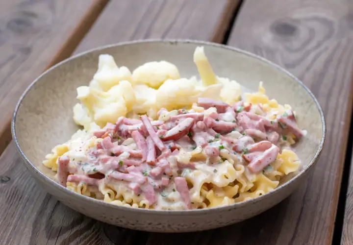 En skål med krusig pasta och skinksås, serverad med blomkål. Enkel och god vardagsmat.