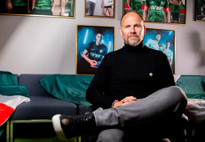 Trener Śląska Wrocław, Ivan Djurdjević, siedzi na kanapie w otoczeniu zdjęć piłkarzy.
