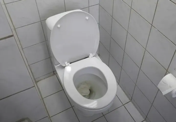 En vit toalett med öppet lock och papper i skålen, vilket indikerar ett stopp i toaletten.