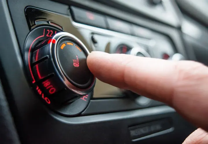 Dedo ajustando el control de temperatura del asiento, mostrando cómo funciona la calefacción de un coche.