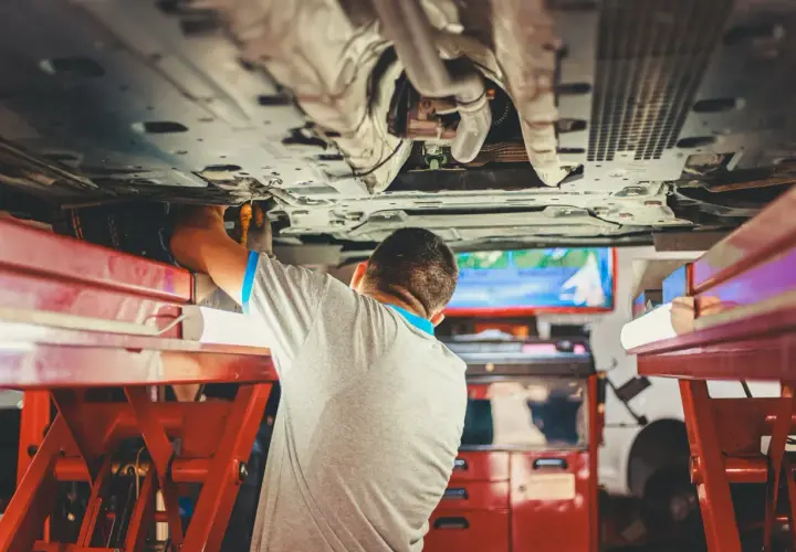 Mechanik pracuje pod samochodem, sprawdzając sworzeń wahacza.