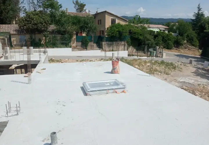 Chantier de construction avec dalle béton fraîchement coulée. Sac de ciment à proximité, peut-être pour estimer le prix dalle béton m2.