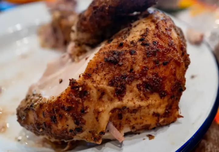 Un morceau de poulet au four cuisson lente, doré et savoureux, servi sur une assiette blanche.